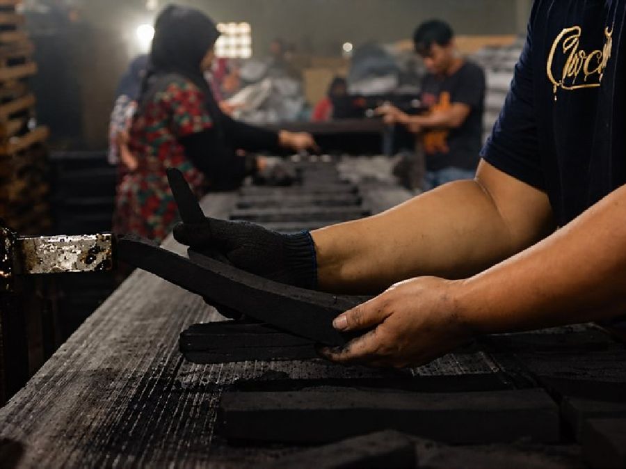 Workers handling freshly molded charcoal bars